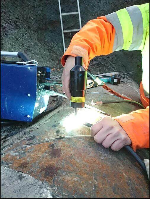 Worker using plasma torch on pipeline