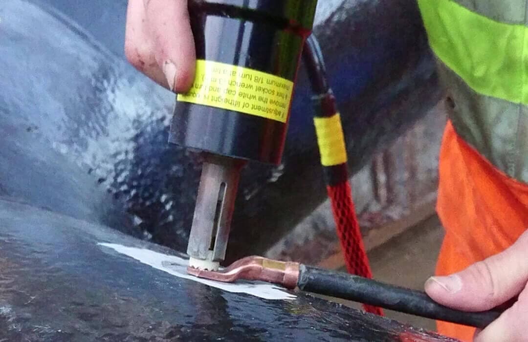 Worker heat-shrinking cable lug onto pipeline