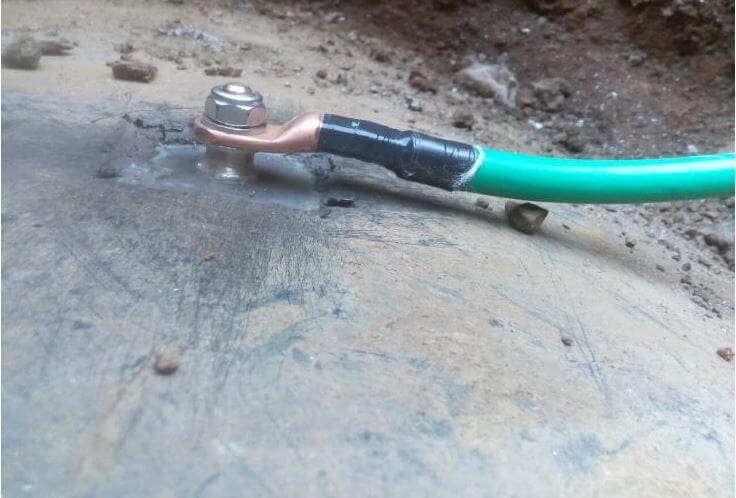 Green grounding cable bolted to metal plate