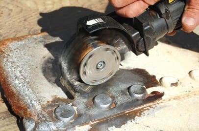 Worker using angle grinder on metal plate