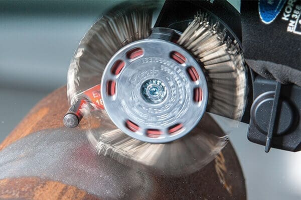 Angle grinder wire brush cleaning rusty metal pipe