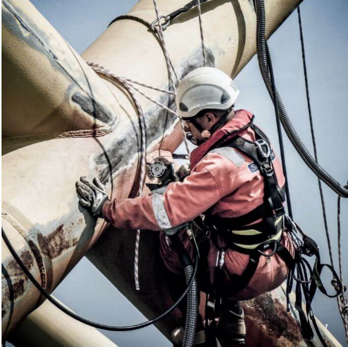 Industrial rope-access worker repairing turbine blade
