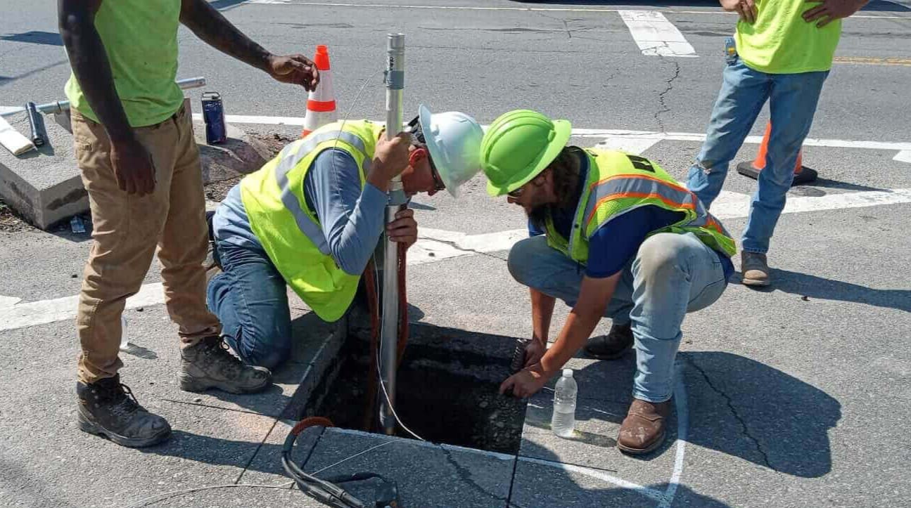 Road crew inspecting open street utility manhole