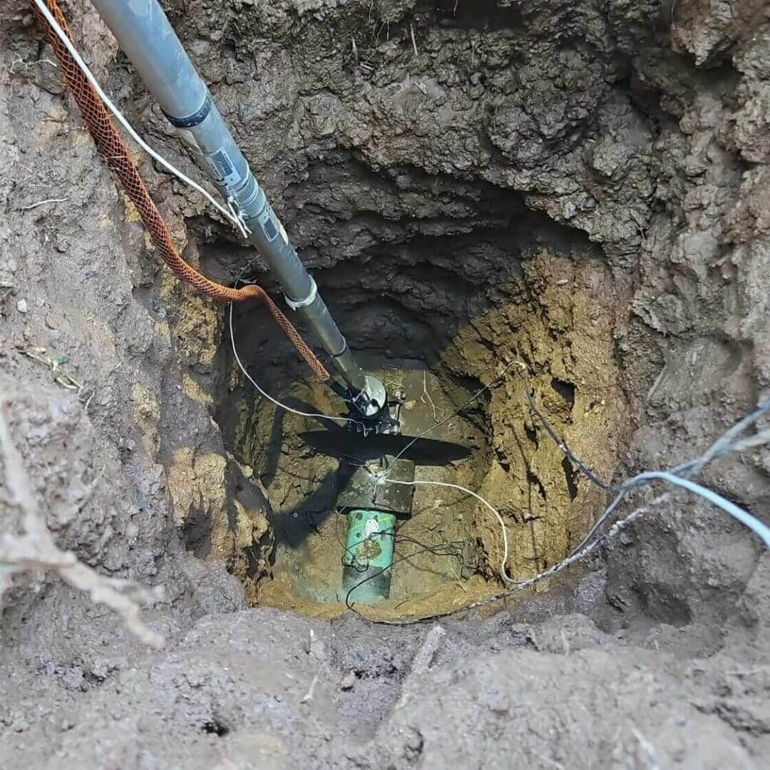 Excavated hole revealing buried well pump assembly