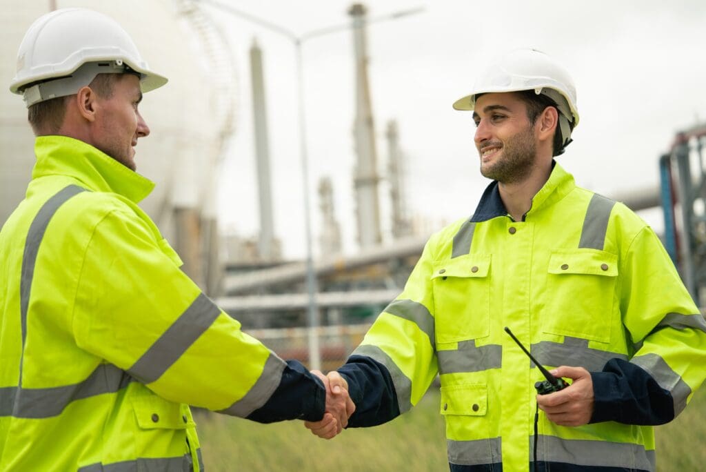 Two workers in high-visibility jackets shaking hands