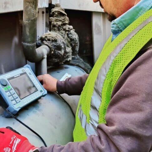 Technician inspecting pipeline with handheld device