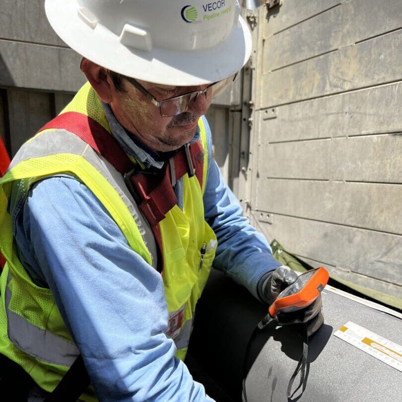 Worker inspecting insulated pipe with handheld device